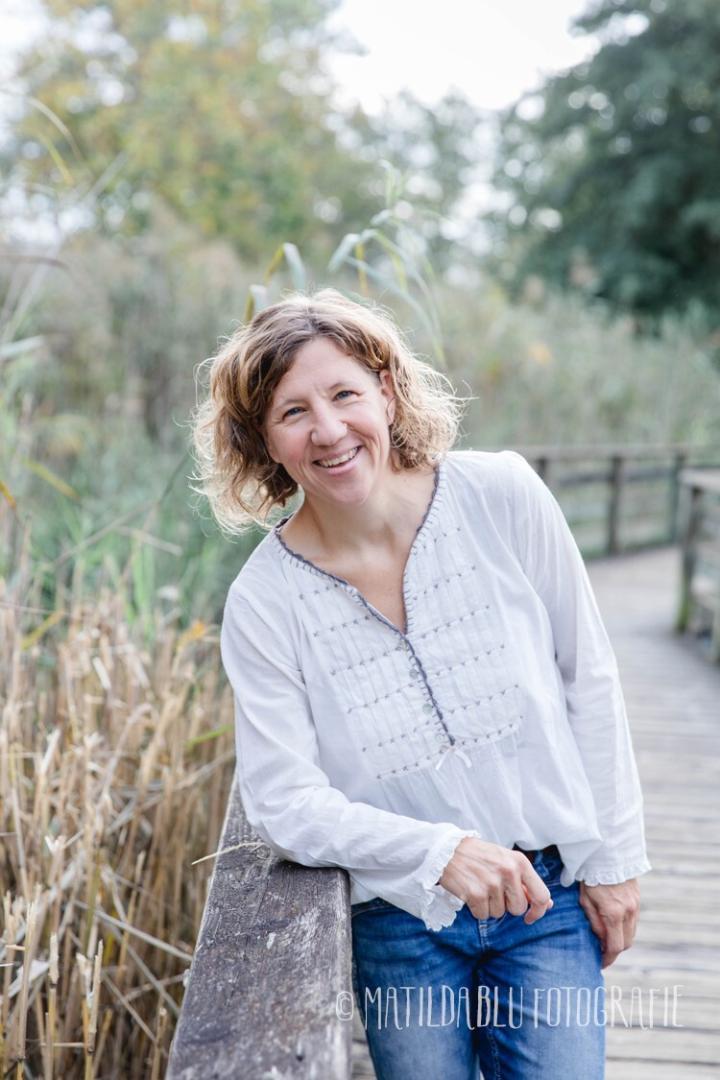 Eine Frau lehnt sich an einen Holzzaun in der Natur.